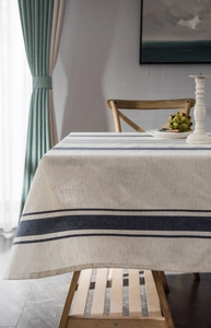 Close-up of beige cotton linen tablecloth with navy blue stripes in a cozy dining setting
