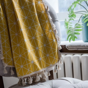 Yellow geometric tassel curtain on a gray sofa in a bright, cozy living room setting