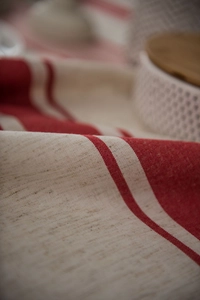 Macro shot of rustic linen tablecloth featuring red striped patterns and natural texture
