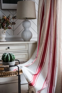 Detail of red and white striped kitchen curtain fabric texture in a cozy home setting