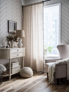 Close-up of linen curtain with black polka dots and decorative tassel trim details