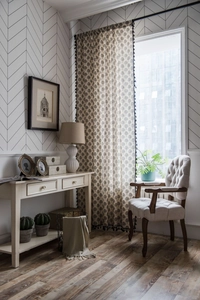 Detail of cotton linen curtain with tree print and black tassel trim in a cozy room