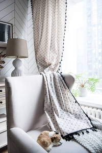 Detail view of daisy print cotton linen curtains featuring black dot patterns and tassel trim