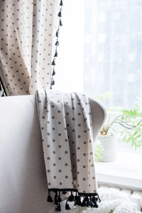 Close-up of cotton linen daisy print curtain with black tassel fringe detail