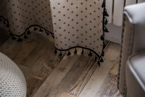 Detail of beige cotton linen curtain with black star prints and delicate fringe tassel hem
