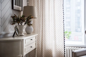 Detail of linen curtain with black daisy print and decorative bohemian side tassels