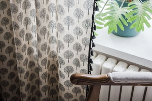 Detail of cotton linen curtain featuring gray tree print and black tassel fringe trim