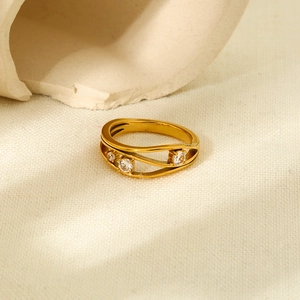 Détail de la bague ondulée en acier doré ornée de trois pierres de zircon cubique