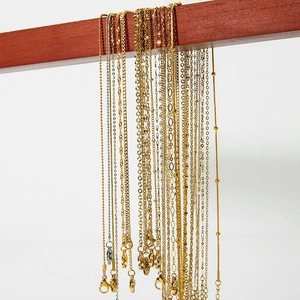 Assorted gold and silver stainless steel basic chain necklaces displayed on a wooden stand