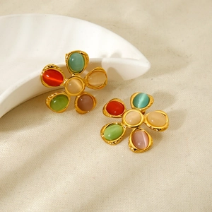 Detalle de pendientes de flor con piedras ojo de gato de colores y acabado martillado de 18K