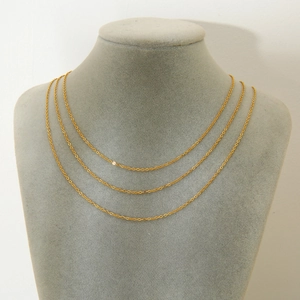 Close-up of three layered 18K gold plated stainless steel O-chains on a gray display stand