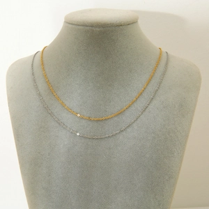 Detailed view of 18k gold and silver stainless steel layered necklaces on jewelry stand