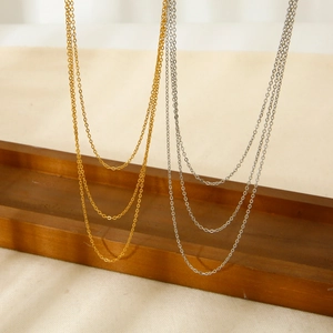Minimalist 18K gold and silver stainless steel O-chain necklaces layered on wooden tray