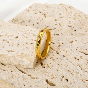 Detail of 18k gold plated ring featuring colorful star-set zircons on travertine stone