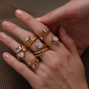 Close-up of elegant stackable gold stainless steel rings with pear and square cut zircons