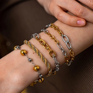 Close-up of five layered gold and silver mixed bracelets on a model's wrist