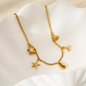 Dettaglio di collana dorata in acciaio inossidabile con ciondoli tartaruga e stella marina