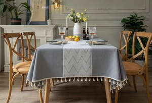 Detail of grey textured tablecloth with white herringbone runner and elegant fringe edges