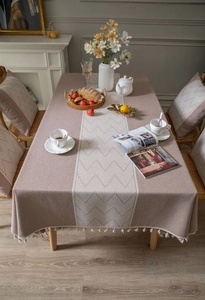 Detail of coffee linen-textured tablecloth featuring ivory geometric patterns and tassels