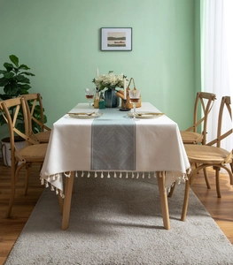 Détail de nappe en lin blanc cassé avec chemin de table géométrique vert et franges