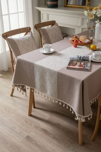 Detail of coffee linen tablecloth with geometric weave pattern and cotton tassel trim