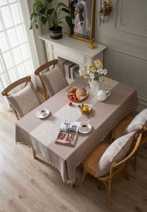 Detailed view of khaki linen textured tablecloth with wavy patterns and elegant fringe trim
