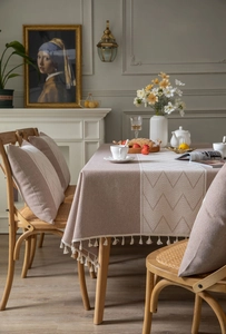 Detailed view of beige and coffee jacquard tablecloth with chevron pattern and tassels