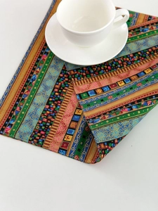 Macro view of bohemian striped table mat with thick woven texture and ceramic cup