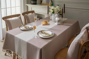 Gros plan sur nappe gris-rose avec bande blanche tissée et franges élégantes