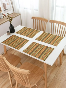 Close-up of four rectangular placemats with warm bohemian striped patterns on a table