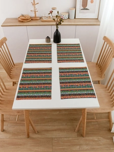 Detail of four bohemian striped placemats on a white dining table in a cozy home setting