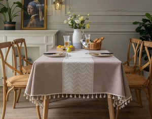 Detail of grey jacquard tablecloth featuring elegant white tassels and wavy pattern