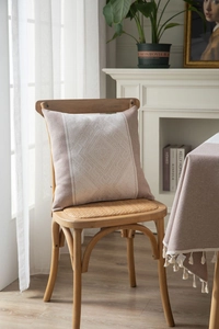 Détail macro du motif tissé géométrique sur le coussin décoratif rose Morandi et beige