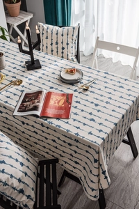 Detail view of blue ripple pattern tablecloth with matching cushion cover on a wooden table