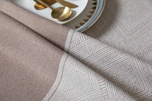 Gros plan sur le motif en losange et couture sergé sur nappe en tissage beige