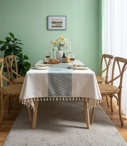 Detailed close-up of beige linen tablecloth featuring wave pattern and fringe edges