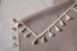 Détail de nappe jacquard à losanges avec texture tissée et pompons faits à la main