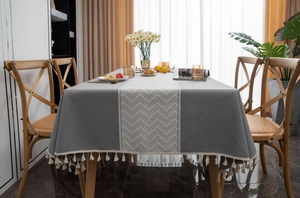 Close-up of grey textured fabric tablecloth featuring wave patterns and white tassels
