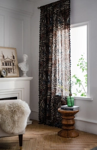 Detail of bohemian leopard and geometric print curtain with black tassel fringe
