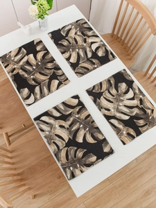 Detail of four-piece tropical monstera leaf placemats set on a modern white dining table