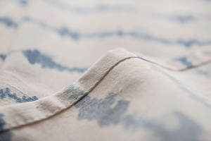 Detail of blue wavy pattern on linen-style tablecloth showing stitching and fabric texture