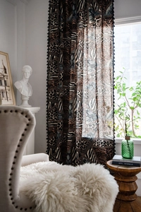 Detail view of Bohemian leopard print curtain with black tassels and geometric patterns
