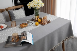 Macro detail of grey textured tablecloth featuring white chevron pattern and tassel fringes