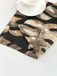 Detail of tropical monstera leaf placemat with espresso cup on white background