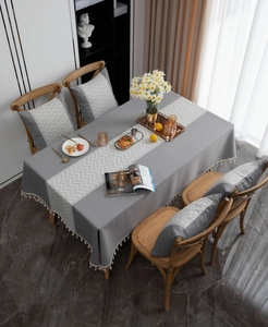 Detail view of gray linen tablecloth with white chevron pattern and cream tassels