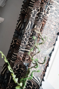 Detailed view of bohemian curtains with leopard zebra patterns and black tassel fringe