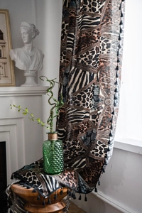 Detail of bohemian leopard print cotton linen fabric with decorative black tassels