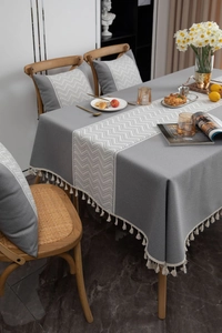 Detailed view of grey linen texture tablecloth with white chevron pattern and tassel edges