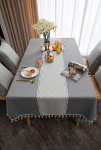 Detail of grey faux linen tablecloth with white chevron pattern and tassel edges