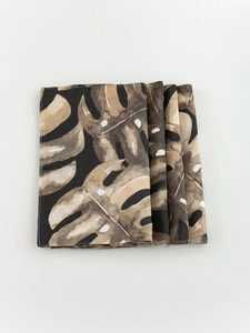 Detail of four tropical Monstera leaf placemats with watercolor texture on black fabric